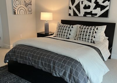 Black and white bedroom with geometric wall art, patterned pillows, and dark bed frame