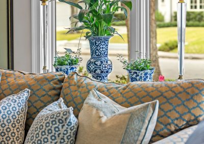 Coastal blue living room detail with patterned pillows, sofa seating, and table lamp