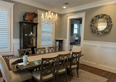 Dining room before refresh with crystal chandelier, dark table, carved mirror, and paneled walls