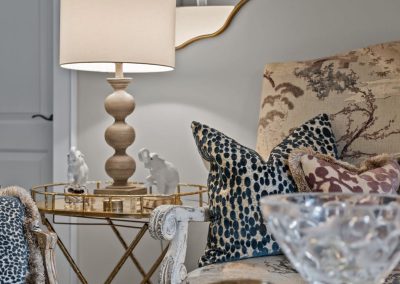 Eclectic office seating with patterned pillows, gold side table, table lamp, and decorative mirror