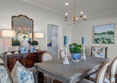 Elegant dining room with blue accents, chandelier, mirror, and styled sideboard