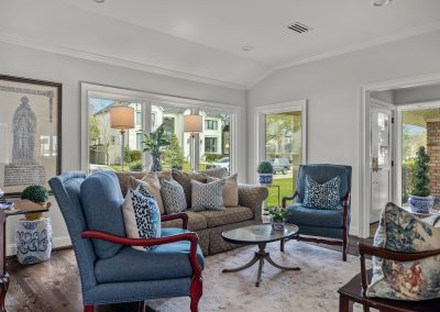 Formal living room with blue accent chairs, patterned seating, framed art, and garden views