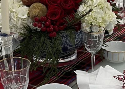 Luxury holiday tablescape with tartan linens, red roses, hydrangeas, and layered place settings