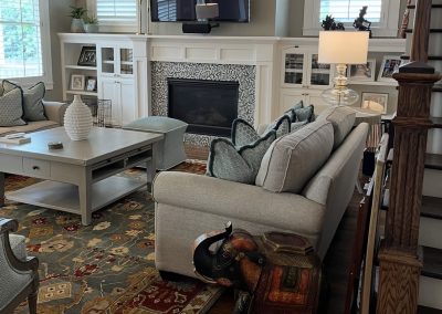 Living room after redesign with neutral sofa, fireplace built-ins, patterned pillows, and layered rug