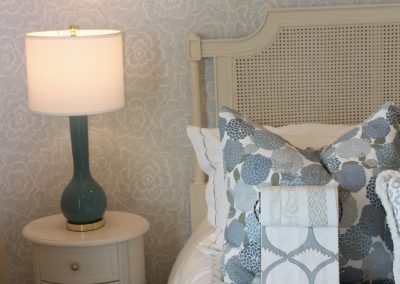 Luxury bedroom styling with blue patterned bedding, textured wallpaper, and elegant bedside decor