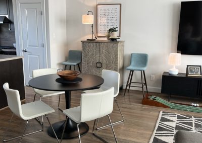 Modern apartment living room with dining table, TV wall, gray seating, and blue accents