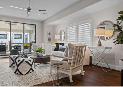 Neutral living room with patterned ottomans, lounge chairs, and balcony doors