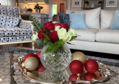 Holiday coffee table centerpiece with red and white roses, evergreen greenery, and red and gold ornaments