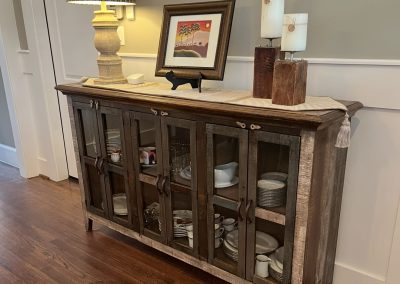 Rustic dining room sideboard before refresh with lamp, framed art, candles, and dish storage