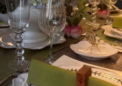 Spring tablescape with pink tulips, hydrangeas, green linens, botanical plates, and glassware