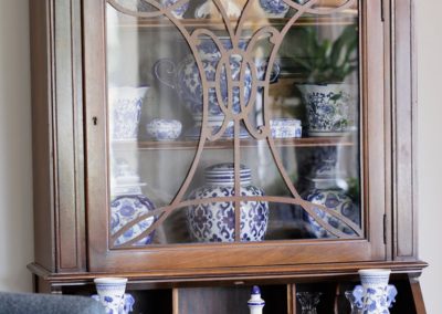 Traditional wood breakfront displaying blue and white porcelain vases, jars, and serving pieces