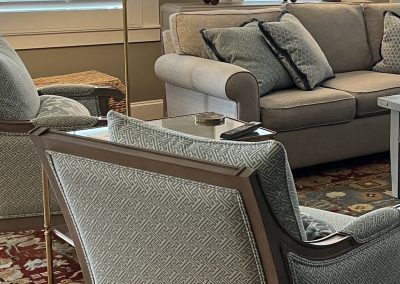 Traditional living room with blue accent chairs, neutral sofa, table lamps, and area rug
