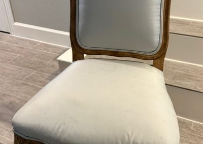 Carved dining chair before upholstery refresh with pale fabric seat and wood frame