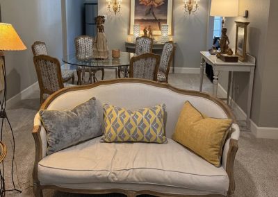 Formal sitting room after refresh with settee, patterned pillows, upholstered chair, and green area rug