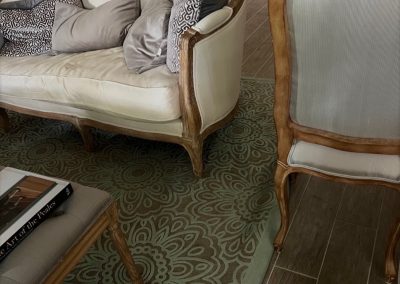 Formal sitting room before seating refresh with settee, dining chairs, glass table, and wall sconces