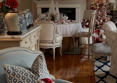 Festive red and white Christmas tablescape featuring peppermint-inspired decor, glass trees, elegant place settings, and a decorated holiday tree.